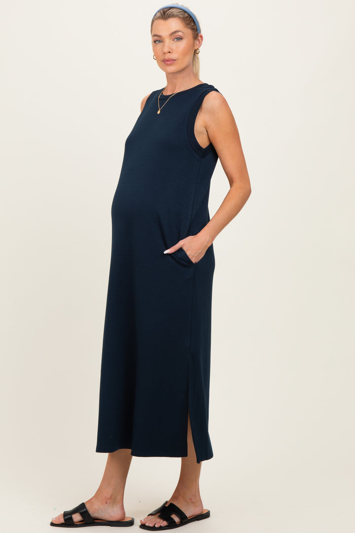 woman wearing a navy blue sleeveless maternity dress with side pockets and a side slit, showcasing her baby bump