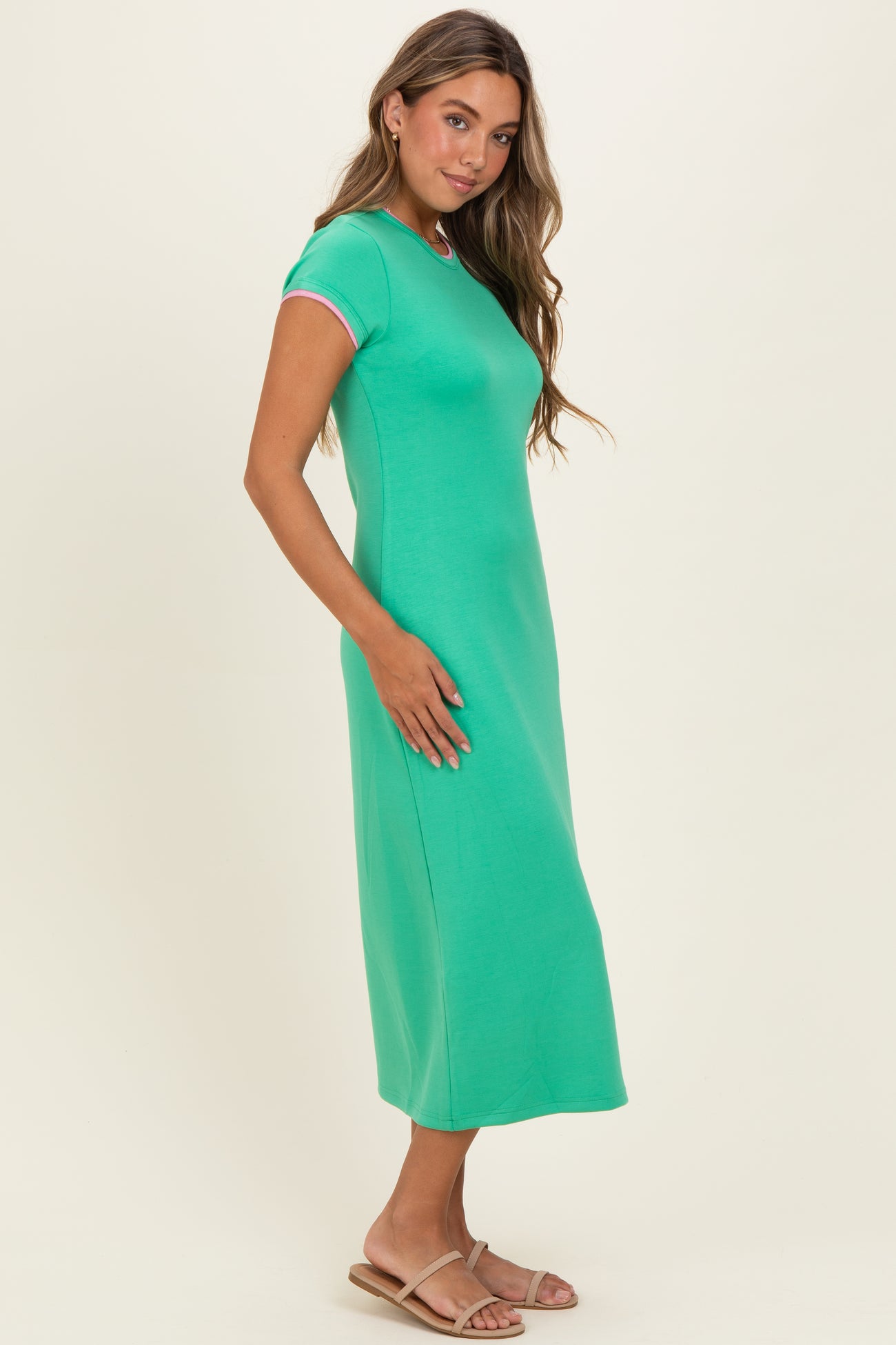 woman wearing a green short sleeve midi dress with a fitted silhouette and a round neckline