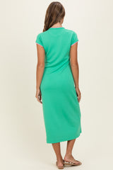 woman wearing a green short sleeve midi dress with a fitted silhouette and a scoop neckline
