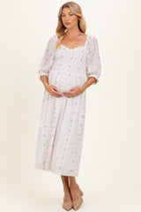 woman wearing a white floral maternity dress with puff sleeves and a square neckline, holding her baby bump