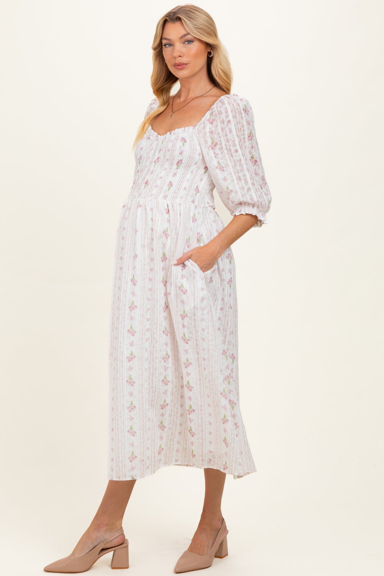 woman wearing a white floral print maternity dress with puff sleeves and pockets