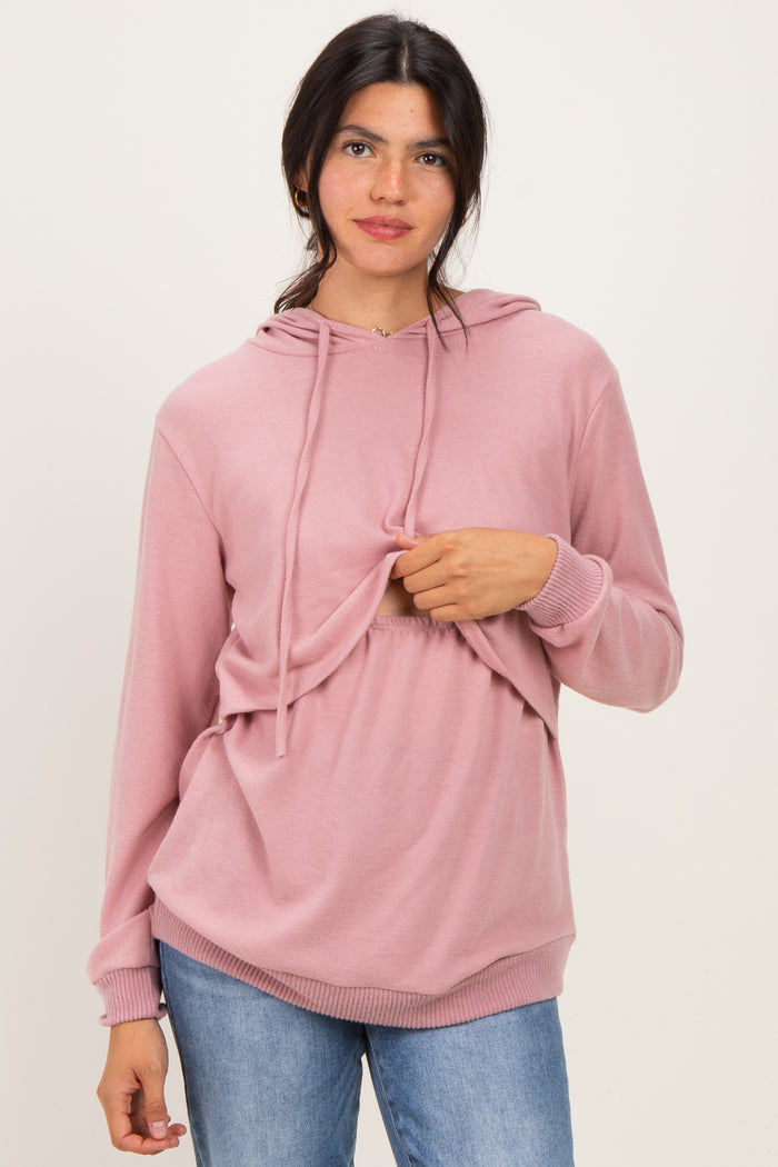 woman wearing a light pink hooded sweatshirt with a adjustable front panel and loose fit, paired with blue jeans