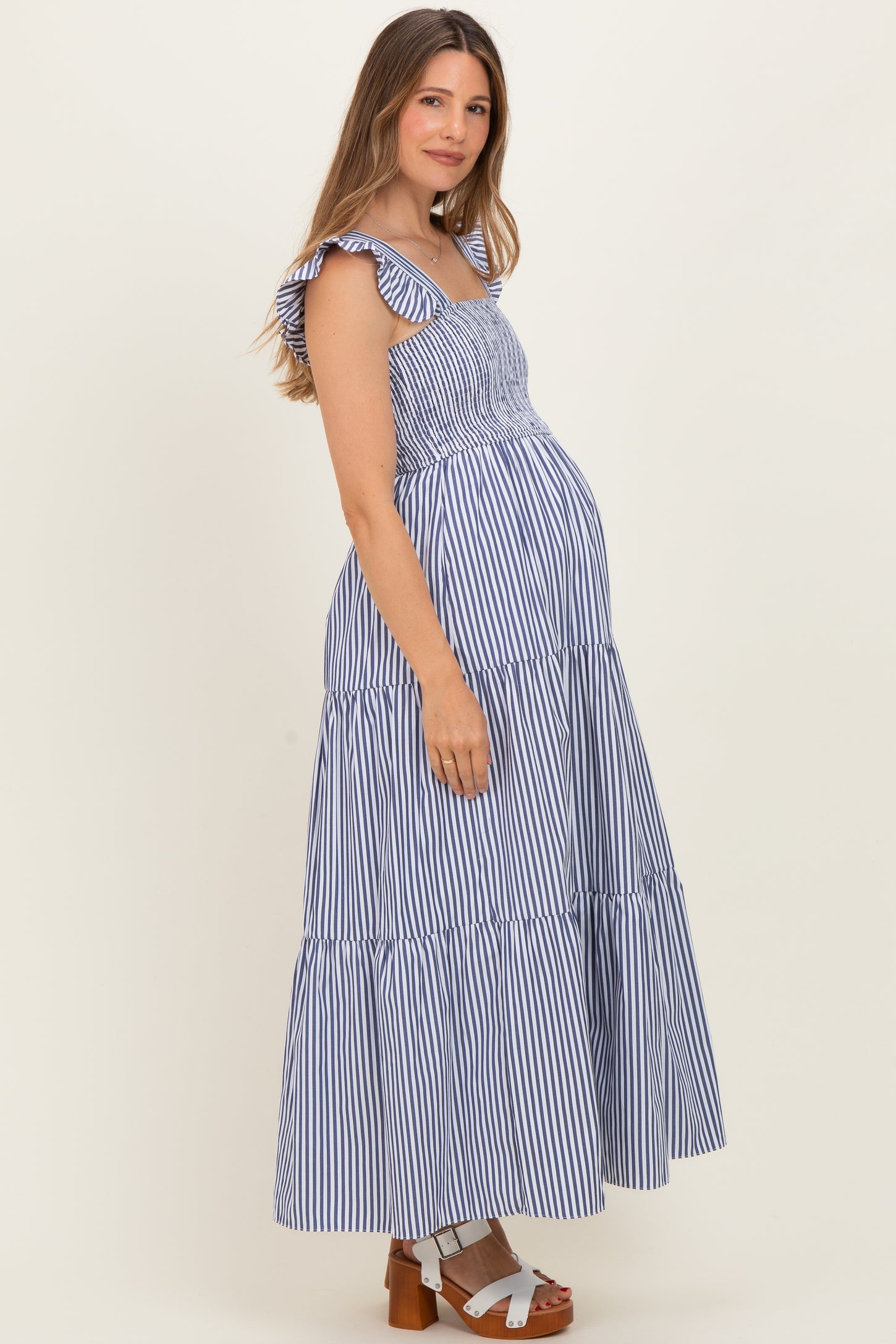 woman wearing a navy and white striped maternity maxi dress with ruffled straps and a visible baby bump