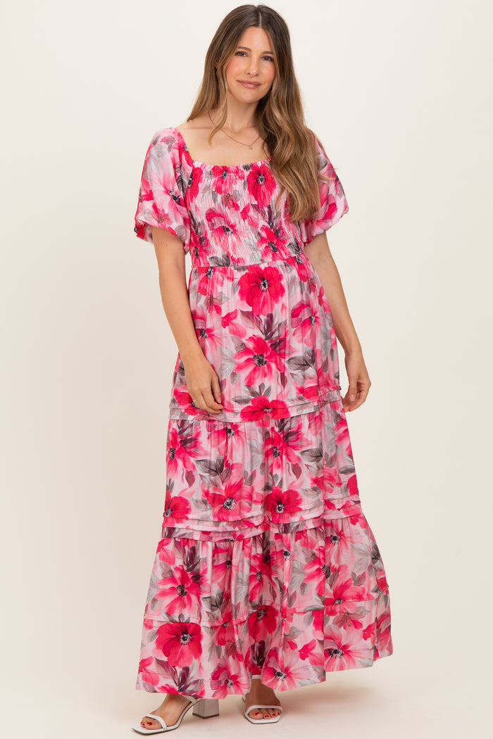 woman wearing a pink floral maternity maxi dress with puff sleeves and a tiered skirt, showcasing her baby bump