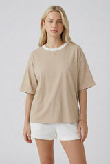 woman wearing a beige oversized t-shirt with short sleeves and white shorts