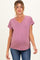 woman wearing a raspberry v-neck maternity top with rolled sleeves and a visible baby bump, paired with jeans