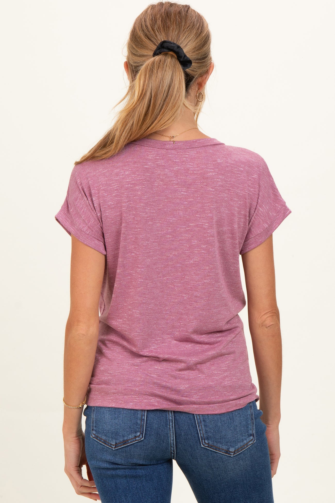 woman wearing a pink short sleeve maternity top, seen from the back, paired with blue jeans