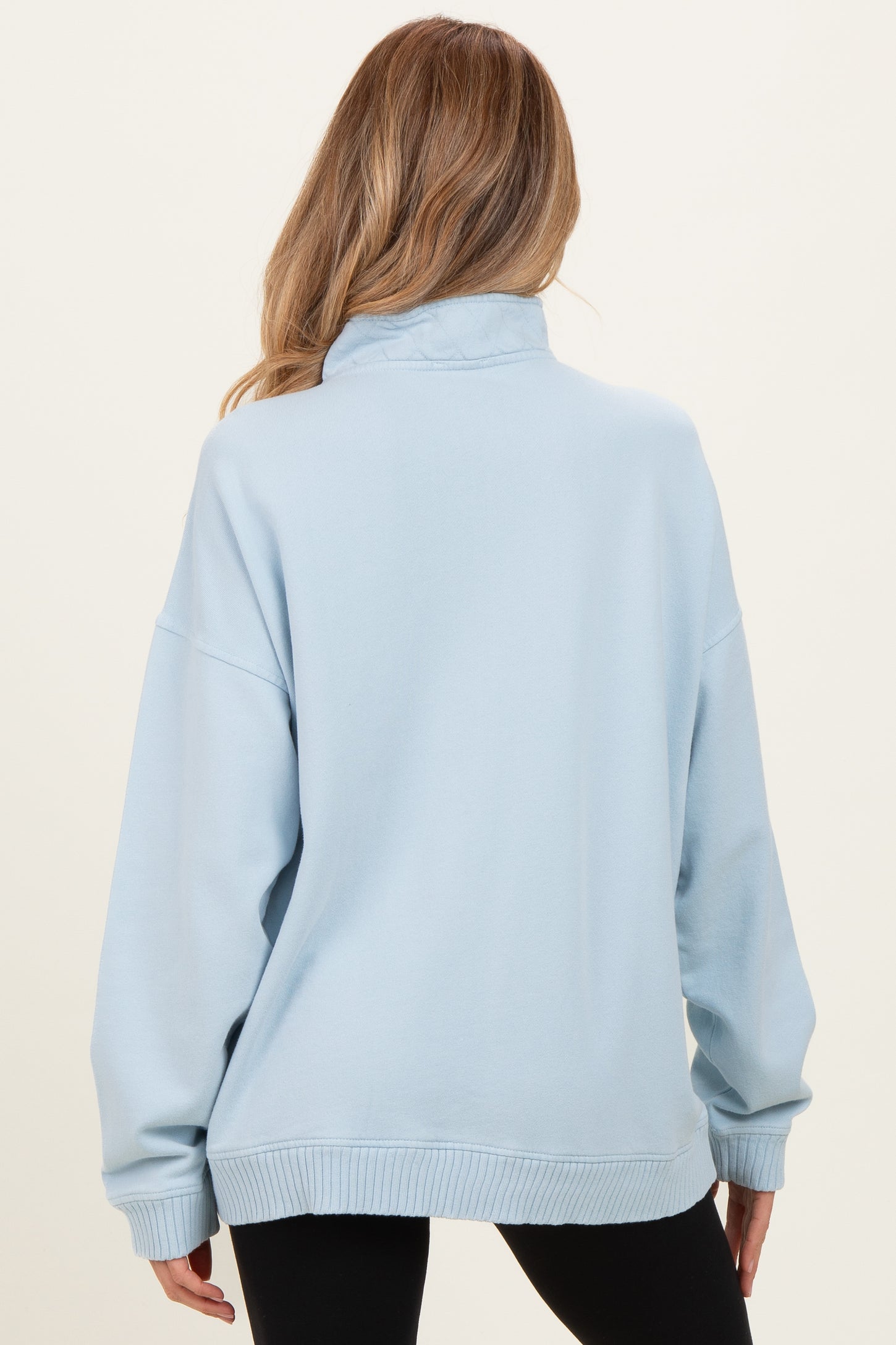 woman wearing a light blue oversized maternity sweatshirt from the back