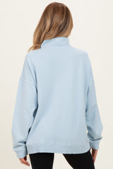 woman wearing a light blue oversized maternity sweatshirt from the back