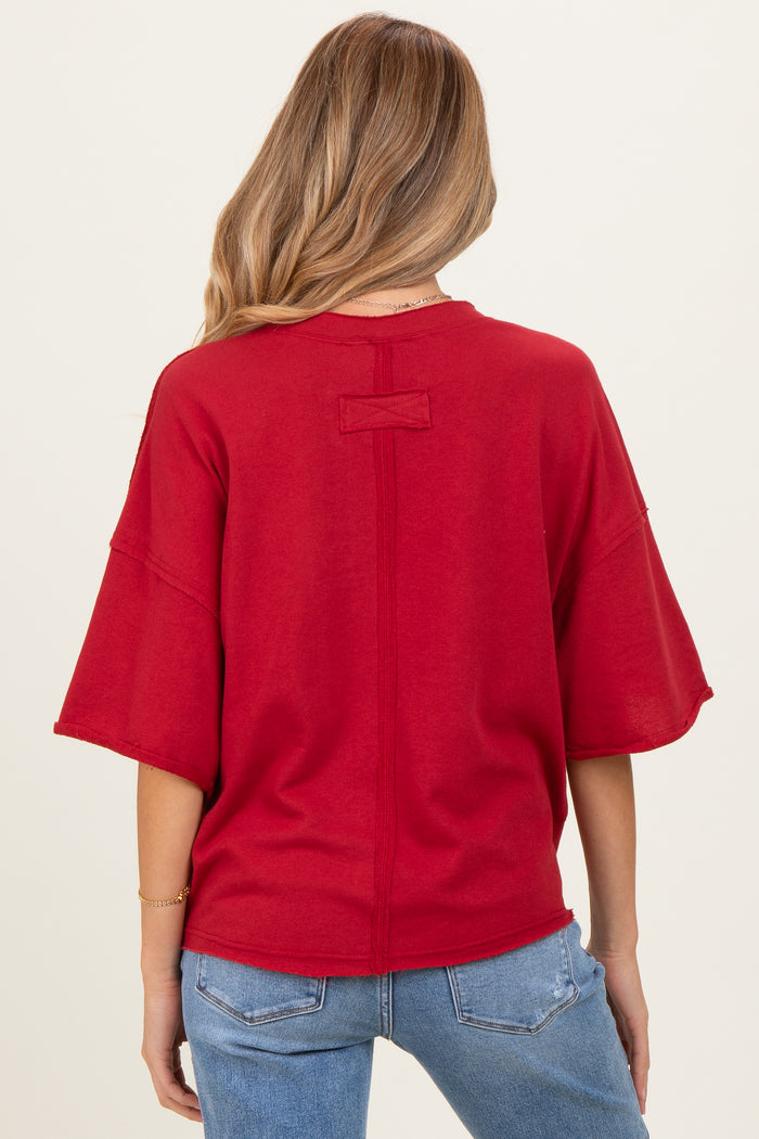 woman wearing a red oversized maternity top with short sleeves and a relaxed fit, viewed from the back