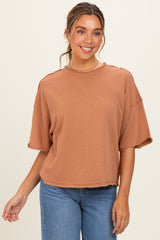woman wearing a rust orange oversized t-shirt with short sleeves and a raw hem, paired with blue jeans