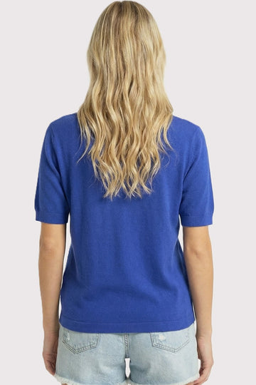 woman wearing a royal blue short sleeve sweater with a relaxed fit and styled with denim shorts