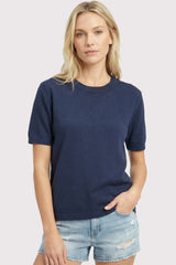 woman wearing a navy blue short sleeve sweater and light denim shorts
