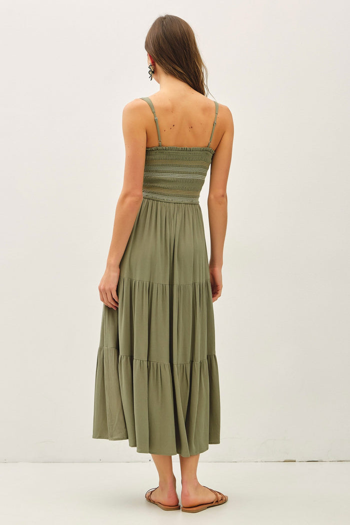 woman wearing an olive green tiered maxi dress with a smocked bodice and thin straps seen from the back