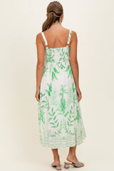 woman wearing a white maxi dress with green leaf prints and adjustable straps, shown from the back