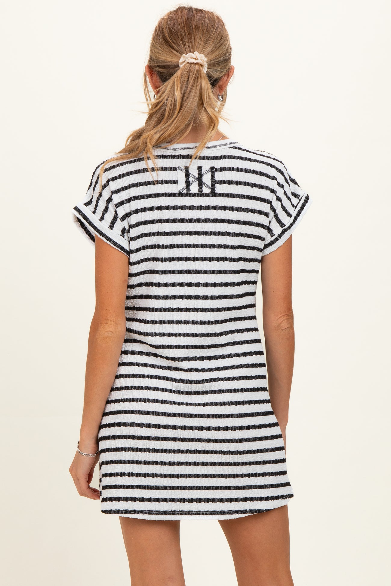 woman wearing a black and white striped maternity dress with short sleeves, showing the back view
