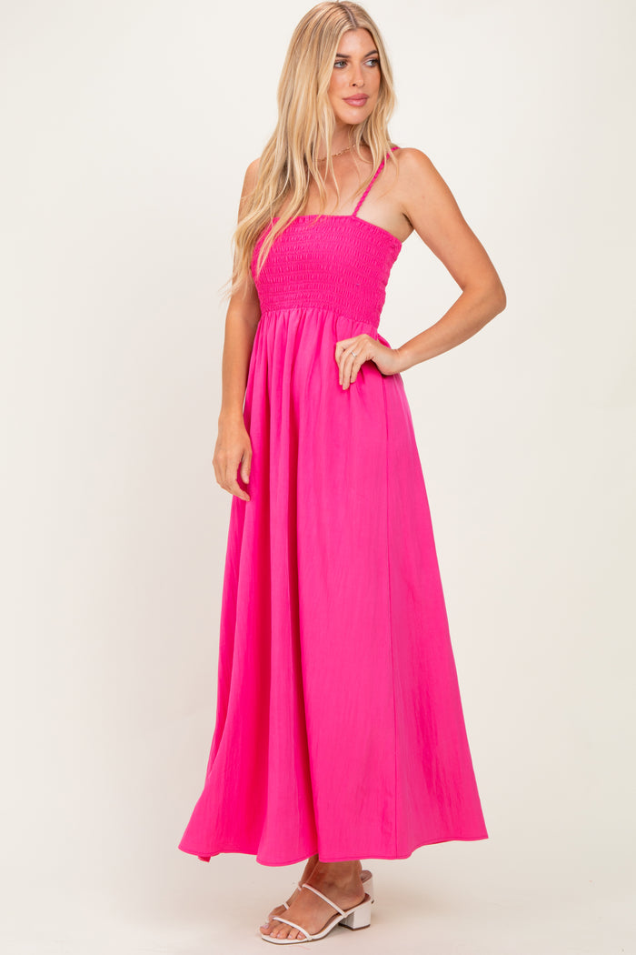 woman wearing a bright pink smocked maxi dress with thin straps and a flowing skirt