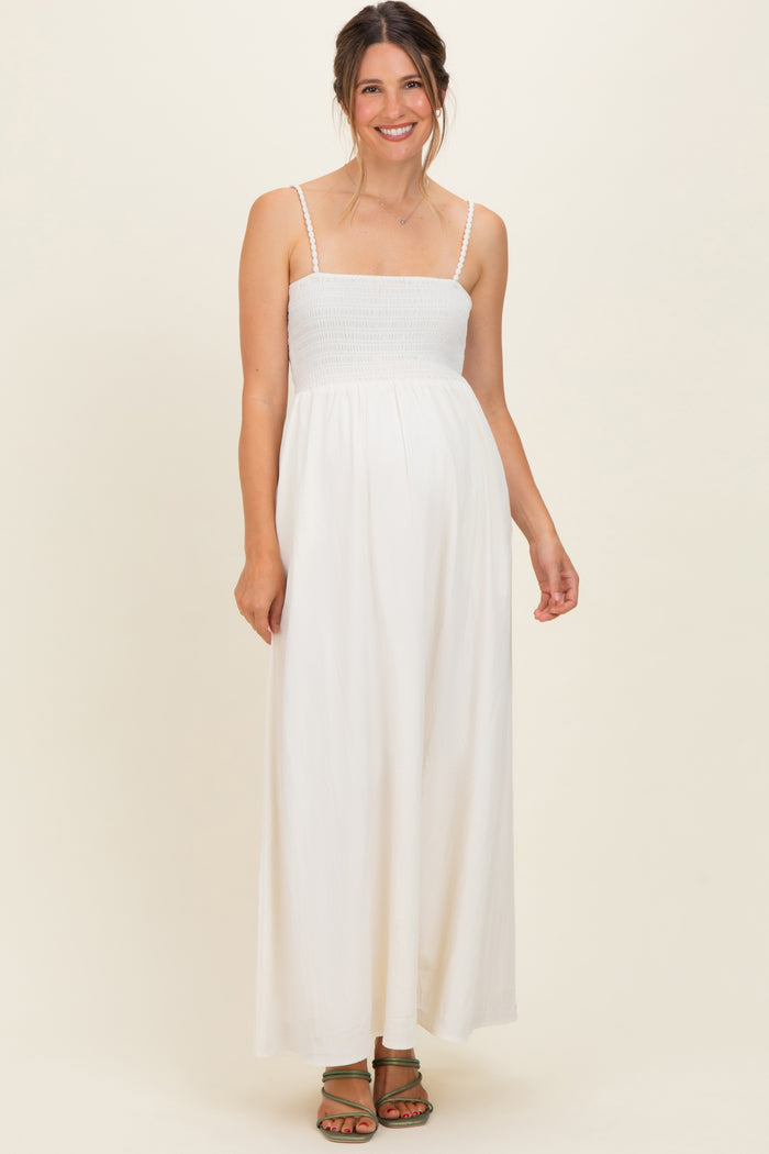 woman wearing a white maternity maxi dress with smocked bodice and adjustable straps, baby bump visible