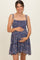 woman wearing a navy floral maternity dress with adjustable straps, gently cradling her baby bump