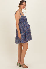 woman wearing a floral maternity dress with adjustable straps and a tiered skirt, showing her baby bump