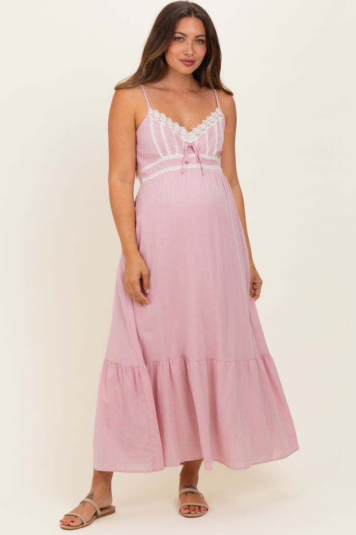 woman wearing a light pink maternity maxi dress with lace details and a baby bump visible
