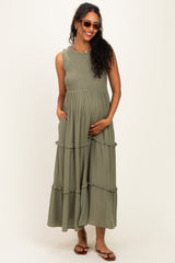 woman wearing a dark green maternity maxi dress with ruffle details and pockets, showcasing her baby bump