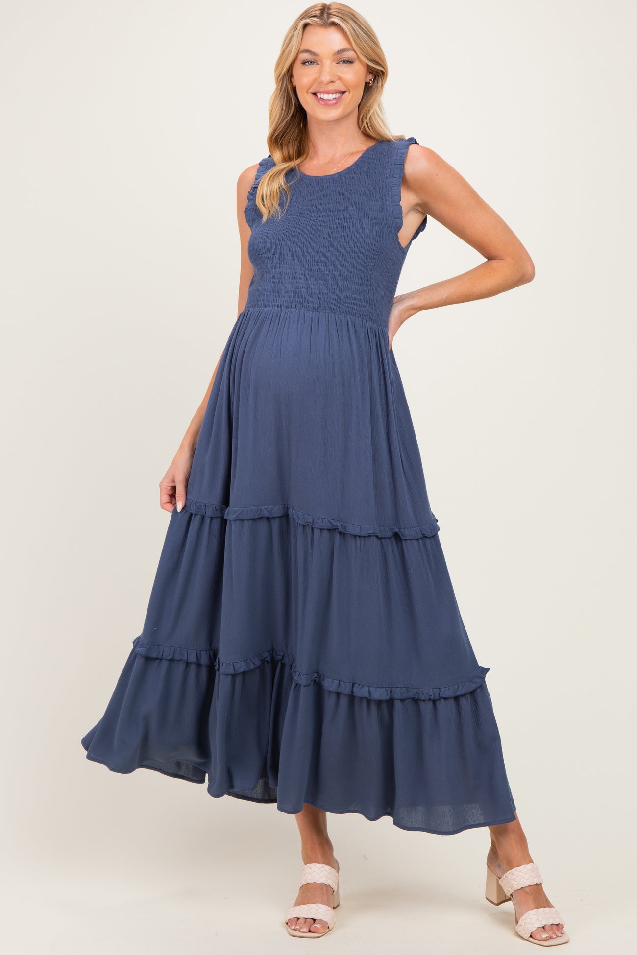 woman wearing a navy blue maternity dress with smocked bodice and tiered ruffled skirt, showcasing her baby bump