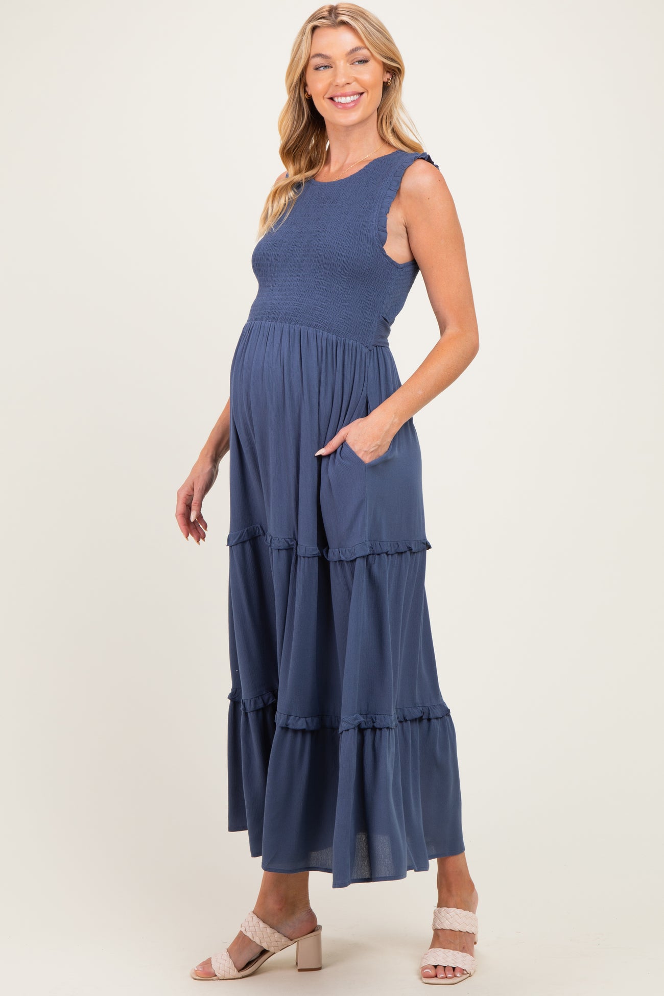 woman wearing a navy blue maternity maxi dress with ruffle tiers and pockets, showcasing her baby bump