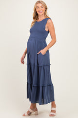 woman wearing a navy blue maternity maxi dress with ruffle tiers and pockets, showcasing her baby bump