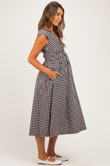 woman wearing a black and white gingham maternity dress with pockets and a visible baby bump