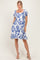 woman wearing a short puff sleeve white dress with blue floral print and a square neckline