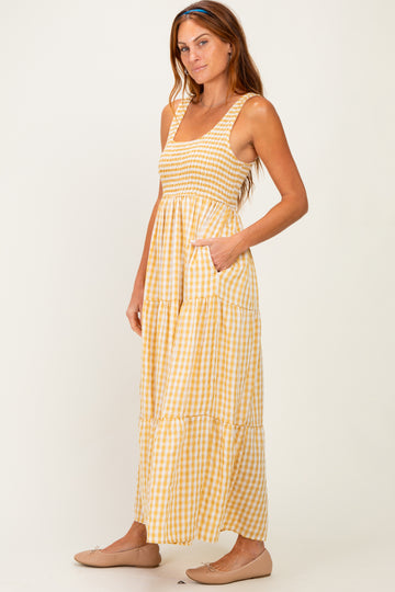 woman wearing a yellow and white gingham print maxi dress with a smocked bodice and pockets