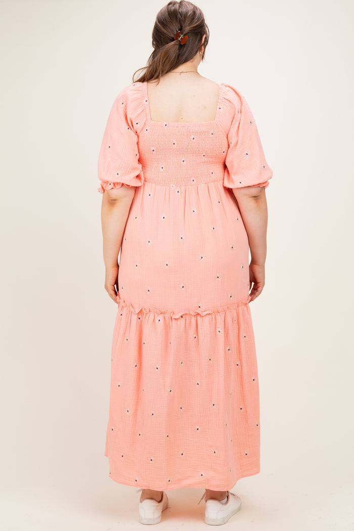 woman wearing a pink maternity plus maxi dress with puff sleeves and floral embroidery on the back