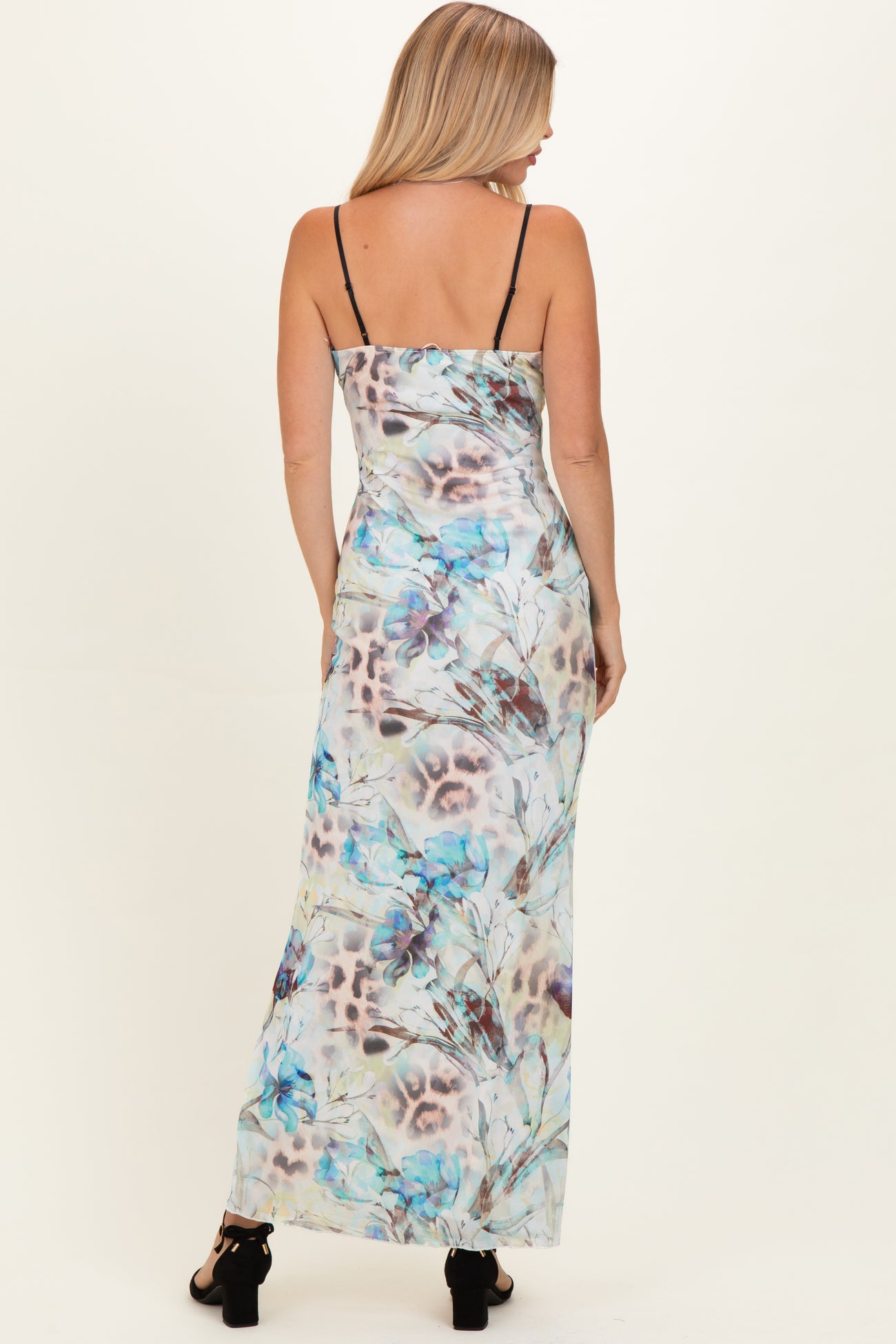 woman wearing a flowy maxi dress with a pastel floral and leopard print design, featuring thin straps and a fitted bodice