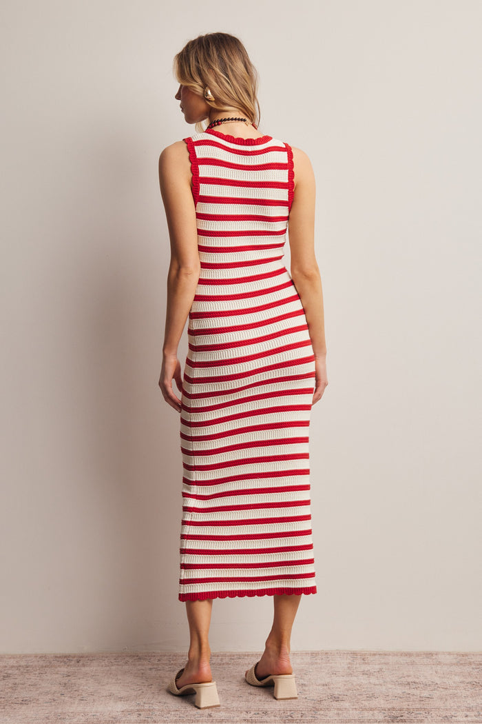 woman wearing a red and cream striped knit midi dress with a fitted silhouette and scalloped hem details, viewed from the back