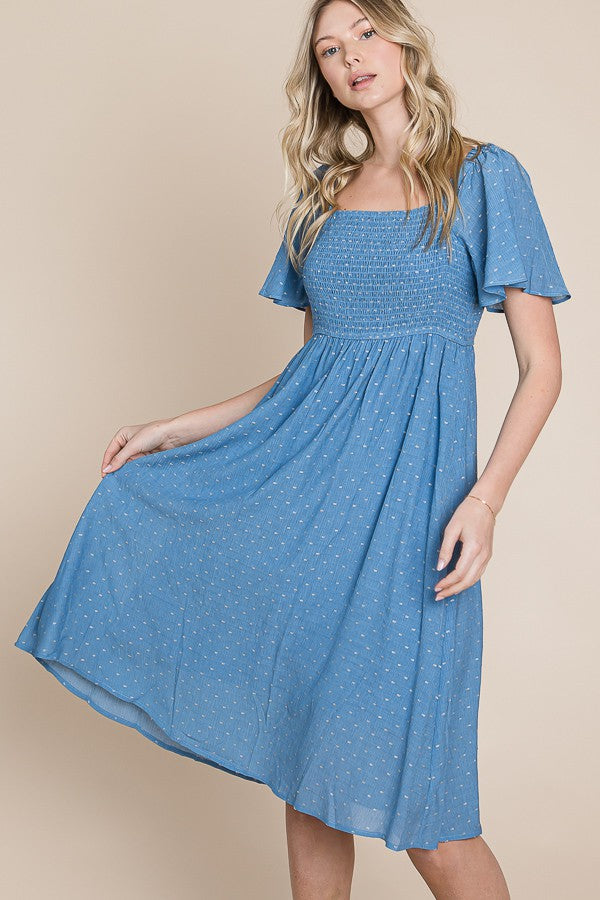 woman wearing a blue smocked midi dress with short puff sleeves and floral details.