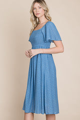 woman wearing a blue short sleeve midi dress with smocked bodice and flutter sleeves