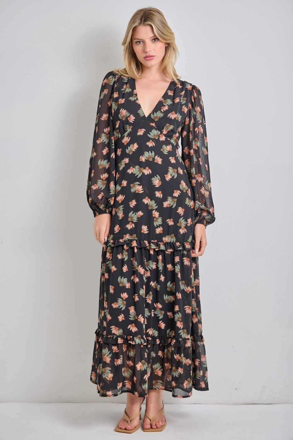 woman wearing a black floral maxi dress with long sleeves and tiered ruffles