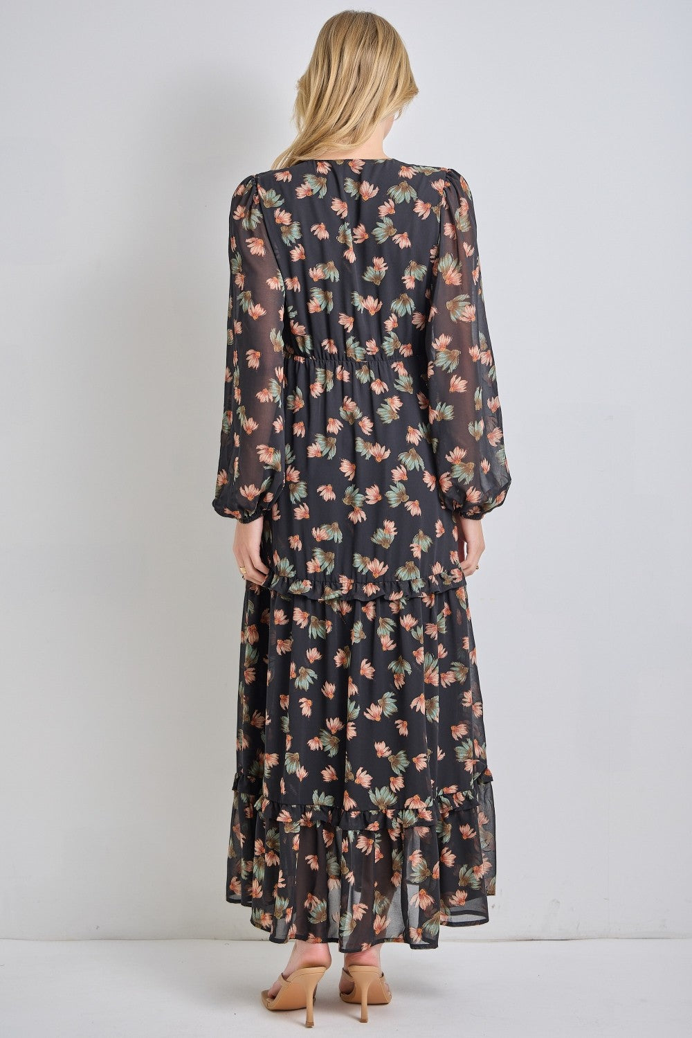 woman wearing a black floral maxi dress with long sleeves and tiered ruffles