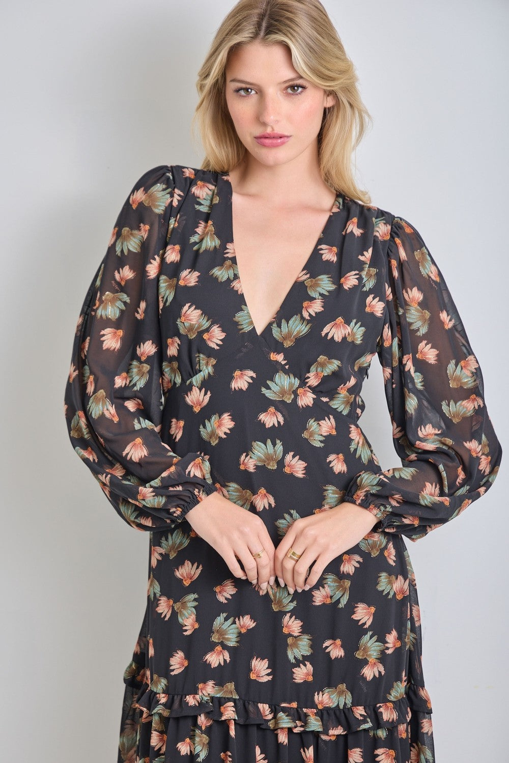 woman wearing a black floral long sleeve dress with a deep v-neck and tiered skirt