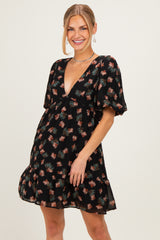 woman wearing a black floral print mini dress with puff sleeves and a deep V-neckline