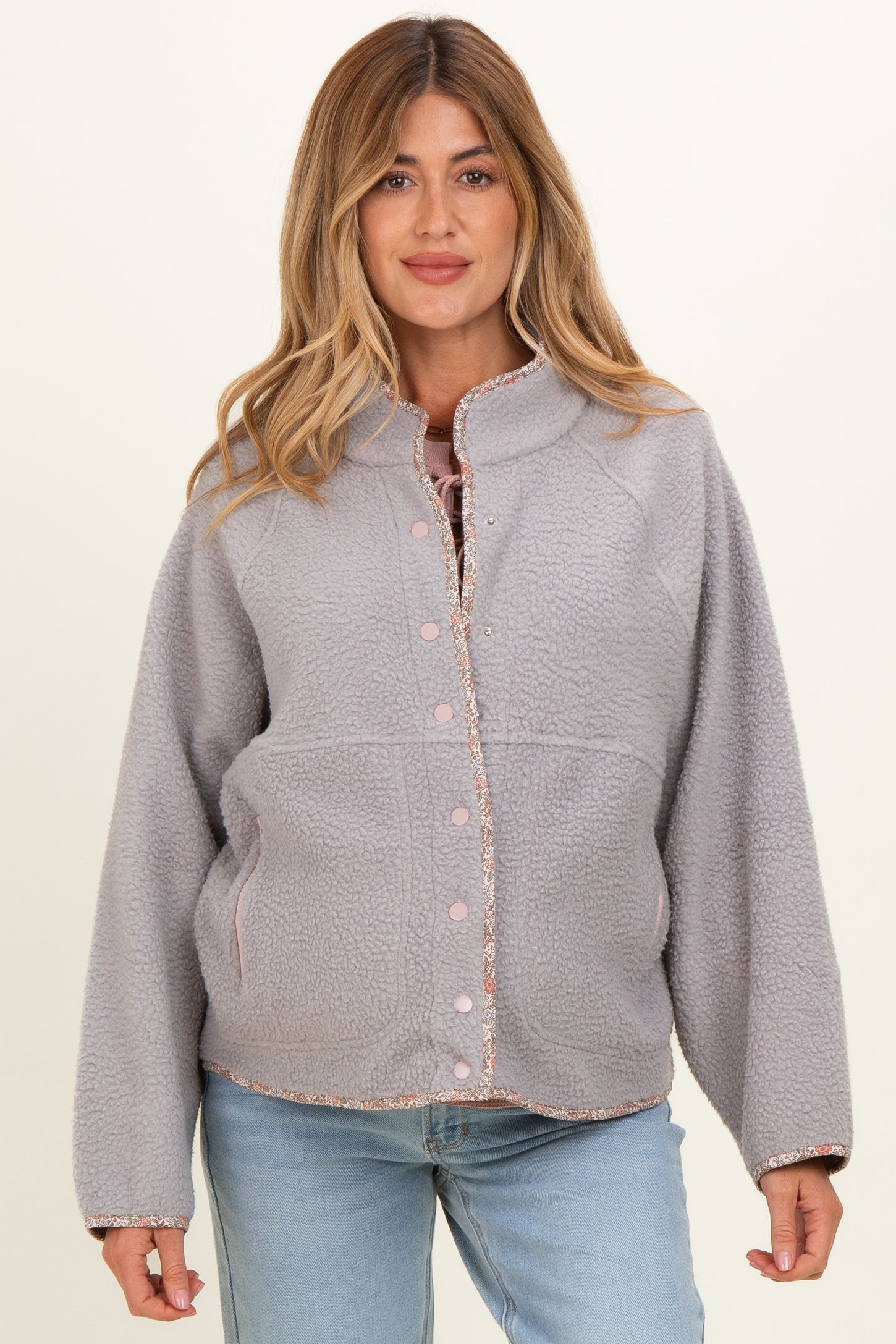 woman wearing a light gray maternity fleece jacket with a button-up front and contrasting trim