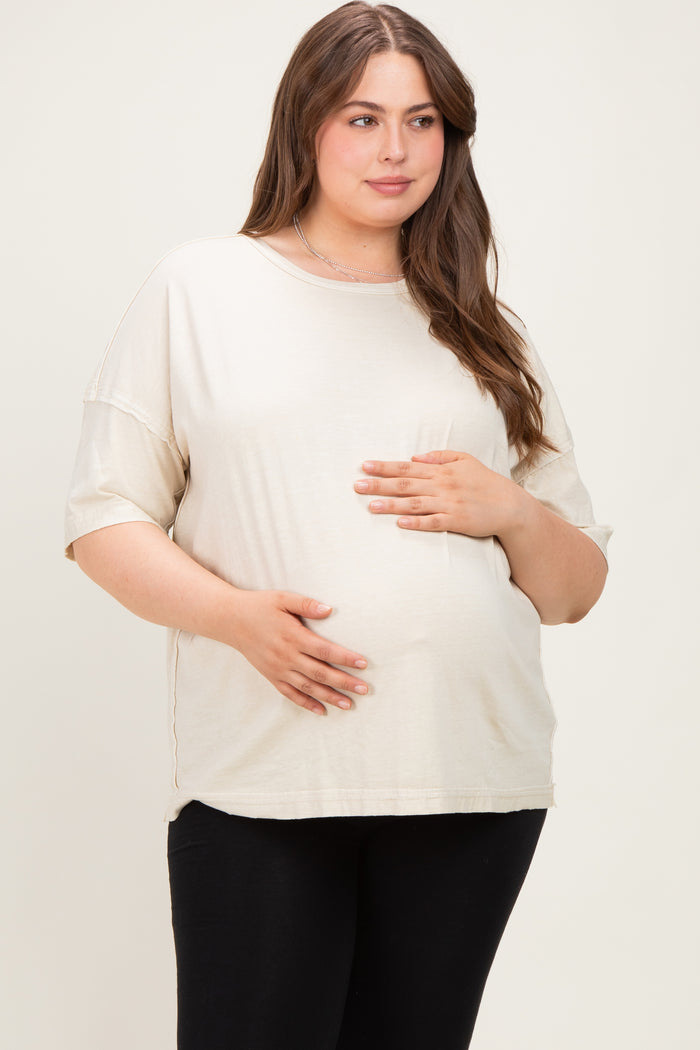 woman wearing a beige maternity plus oversized t-shirt with a visible baby bump and black leggings