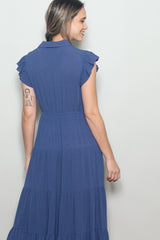 woman wearing a navy blue tiered maxi dress with ruffle sleeves and a collared neckline, shown from the back