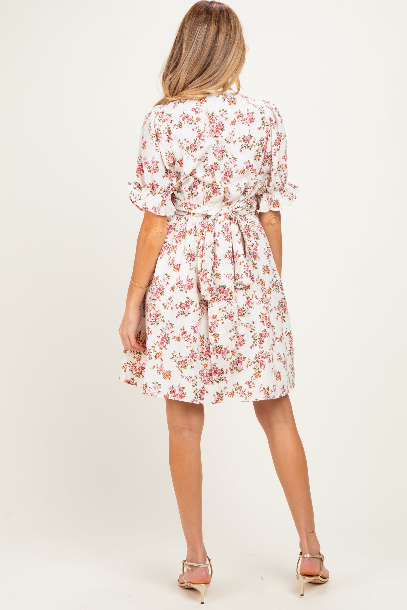 woman wearing a floral print maternity dress with short sleeves and a tie waist seen from the back