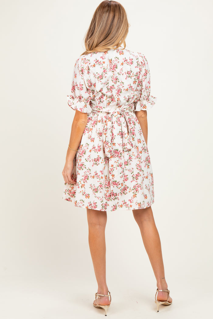 woman wearing a floral print maternity dress with short sleeves and a tie waist seen from the back