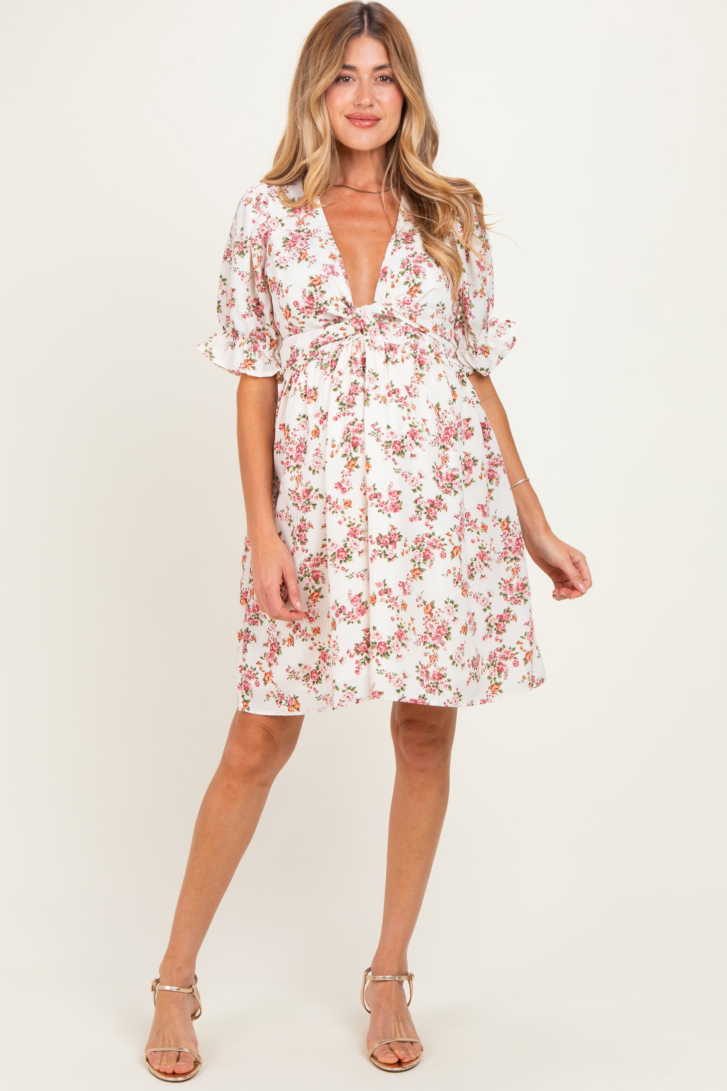 woman wearing a white floral maternity dress with a deep v-neck and ruffled sleeves