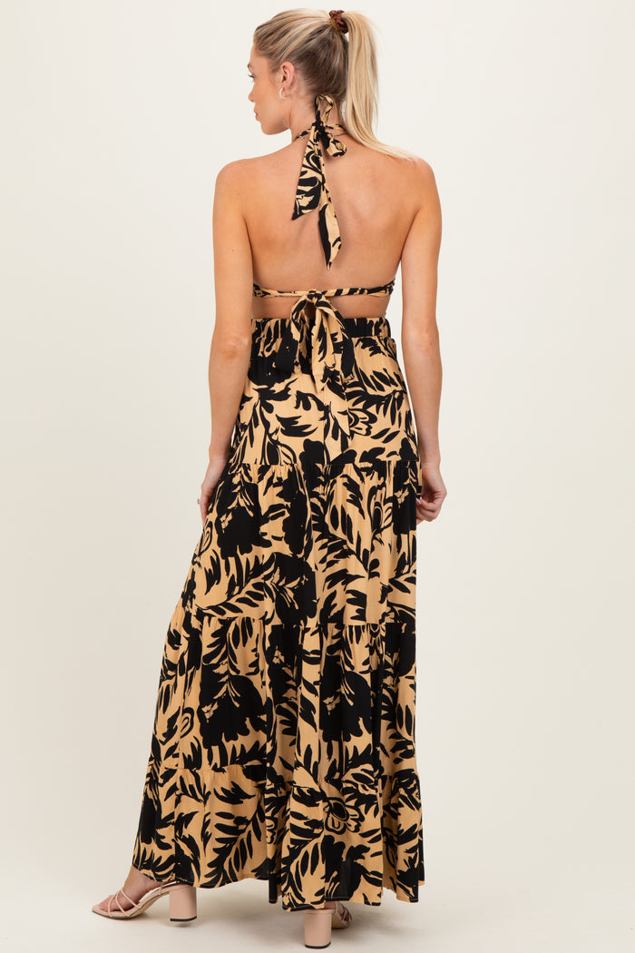 woman wearing a black and beige floral print maternity maxi dress with a halter neck and open back