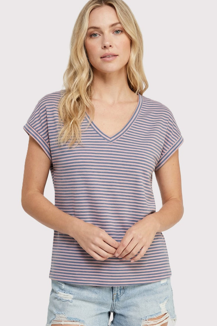 woman wearing a striped purple and white v-neck t-shirt with rolled sleeves and distressed light blue denim shorts