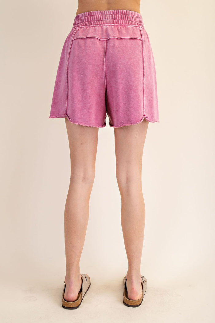 woman wearing pink high-waisted shorts with a raw hem and elastic waistband, shown from the back